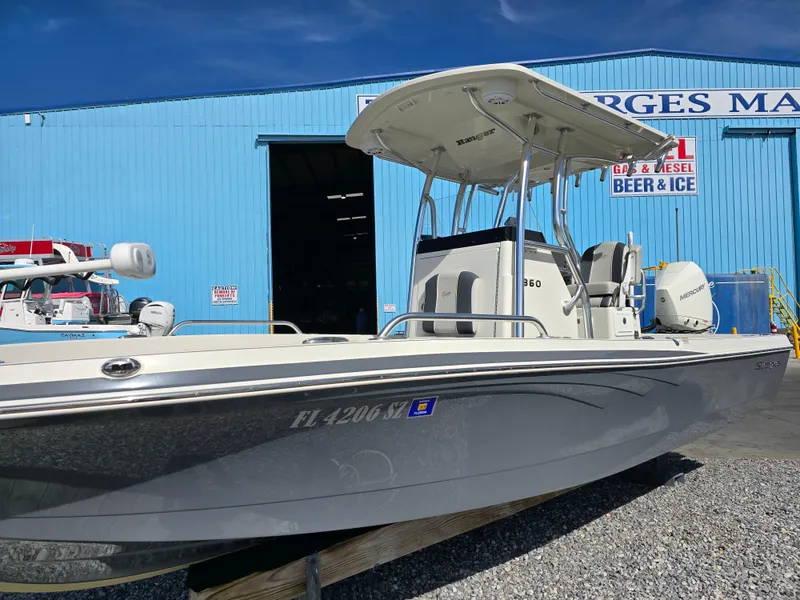 Slide: The Image of 2021 Ranger 2360 Bay boat in front of a blue marina building. - 2