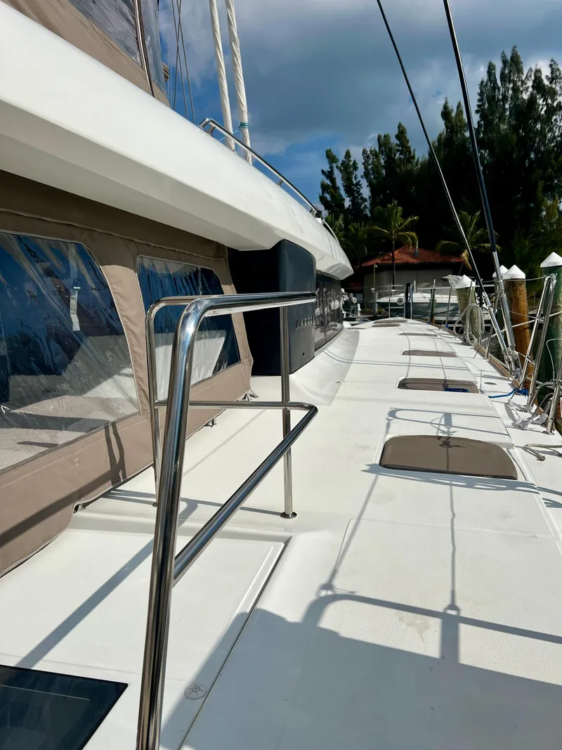 Slide: The Image of 2017 Lagoon 620 yacht deck with sleek design and modern features, docked under a cloudy sky. - 10