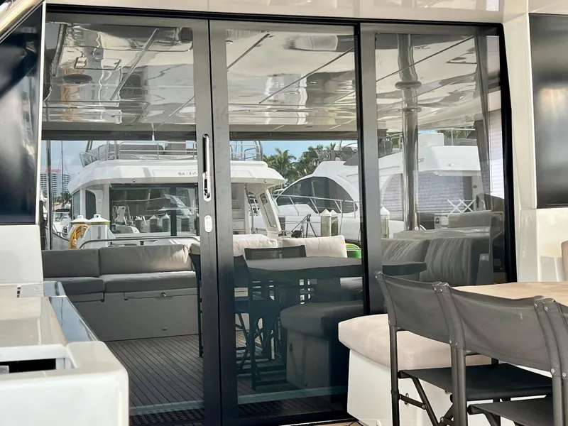 Slide: The Image of Luxurious Lagoon 620 yacht interior with glass doors, showcasing modern seating and elegant design, 2017 model. - 17