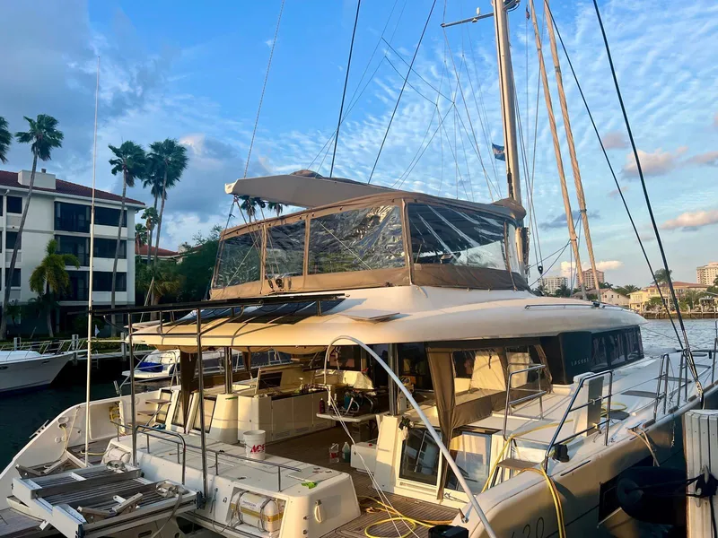 Slide: The Image of 2017 Lagoon 620 catamaran docked at marina, surrounded by palm trees and buildings. - 2