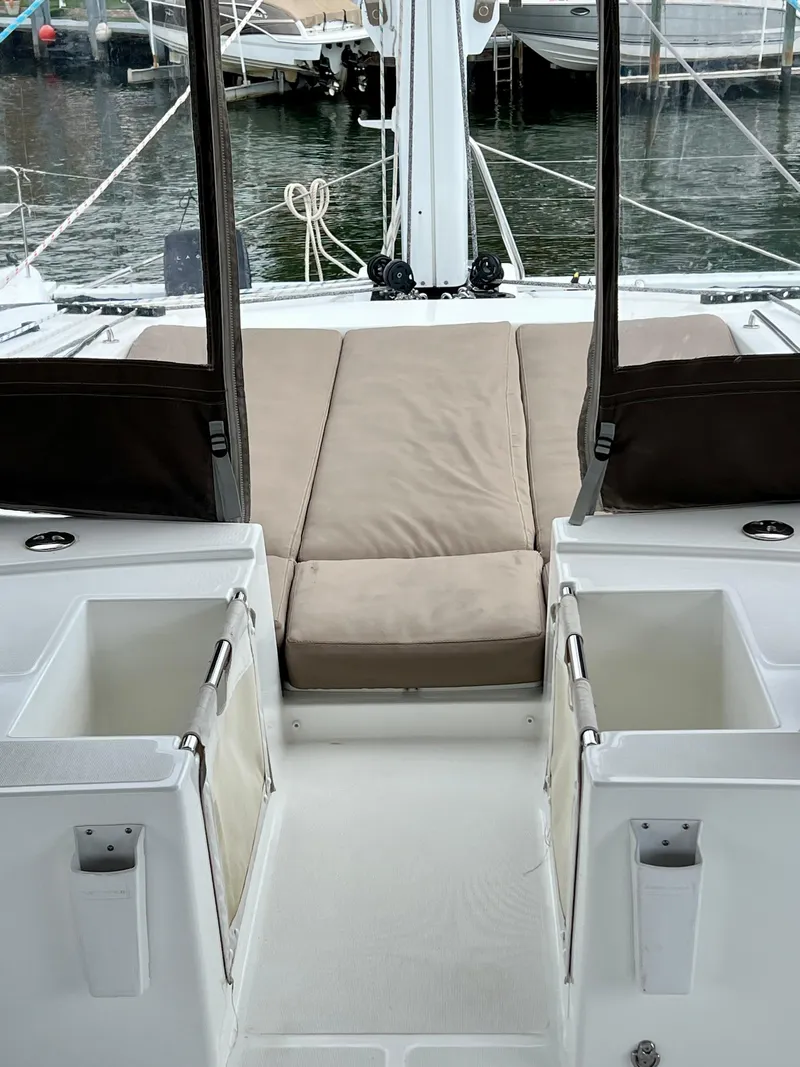 Slide: The Image of 2017 Lagoon 620 yacht interior with beige seating and storage compartments, docked at a marina. - 39