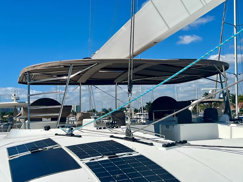 Slide: The Image of 2017 Lagoon 620 catamaran with solar panels and sails, docked under a clear blue sky. - 6
