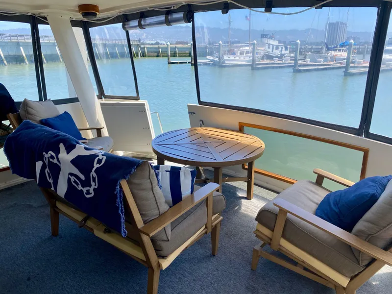 Slide: The Image of 1988 Californian Sundeck Motoryacht interior with cozy seating and marina view. - 10