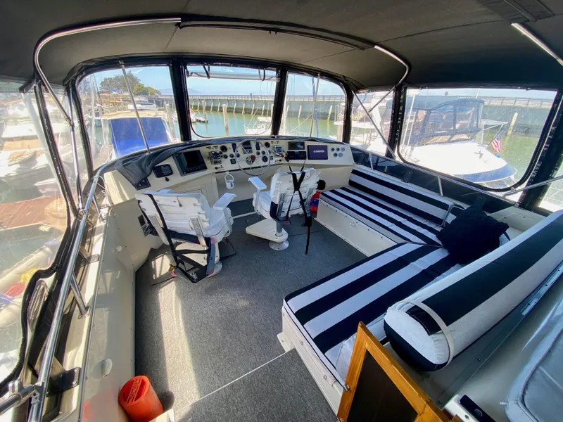 Slide: The Image of 1988 Californian Sundeck Motoryacht interior with striped seating and helm, docked at marina. - 11