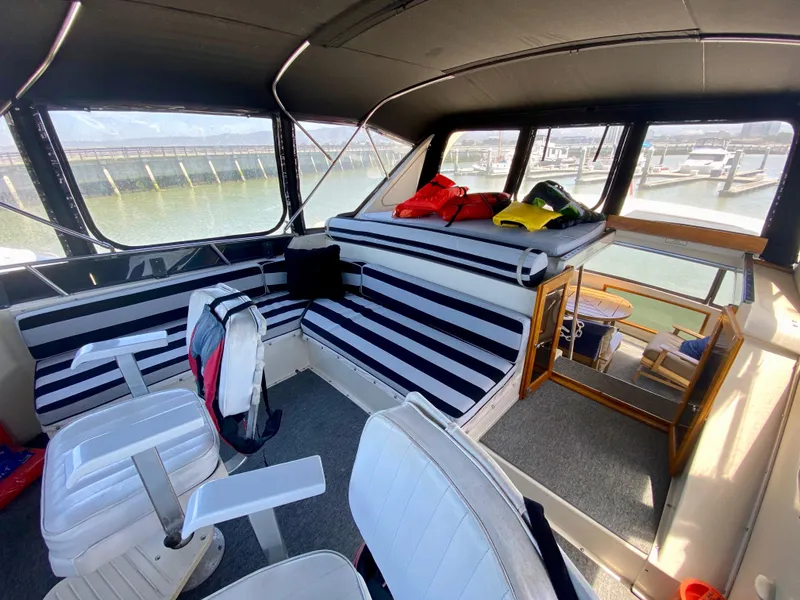 Slide: The Image of 1988 Californian Sundeck Motoryacht interior with striped seating and marina view. - 12