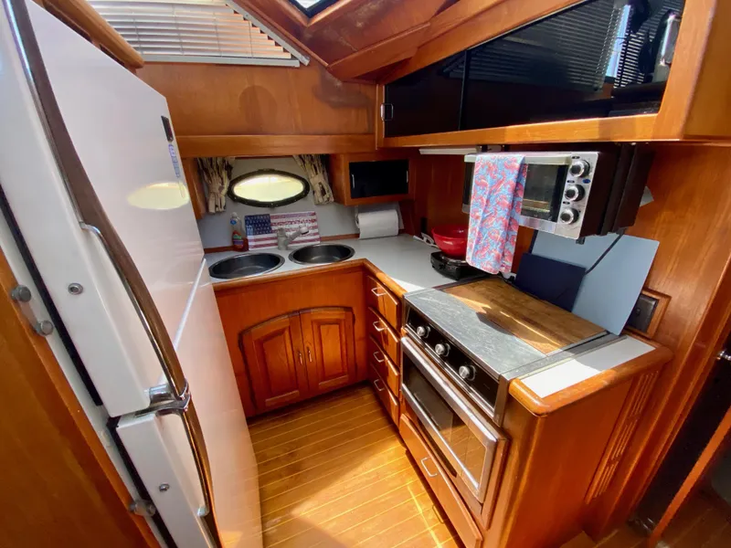 Slide: The Image of 1988 Californian Sundeck Motoryacht kitchen with wood cabinetry, stove, microwave, and refrigerator. - 22