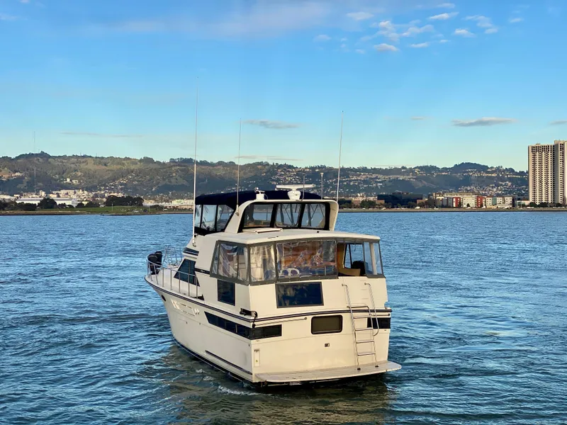 Slide: The Image of 1988 Californian Sundeck Motoryacht cruising on a scenic waterway with cityscape backdrop. - 5