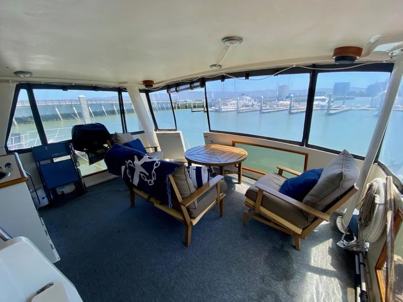 Slide: The Image of 1988 Californian Sundeck Motoryacht interior with seating, table, and marina view. - 7