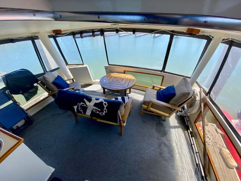 Slide: The Image of 1988 Californian Sundeck Motoryacht interior with seating and table, overlooking water. - 9