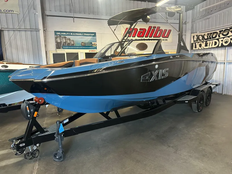 Slide: The Image of 2025 Axis A245 boat in showroom, black and blue design, on trailer. - 2