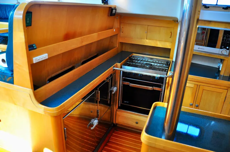 Slide: The Image of Interior of 2000 Roger Hill Cruising Cutter, featuring a modern kitchen with wood cabinetry. - 25