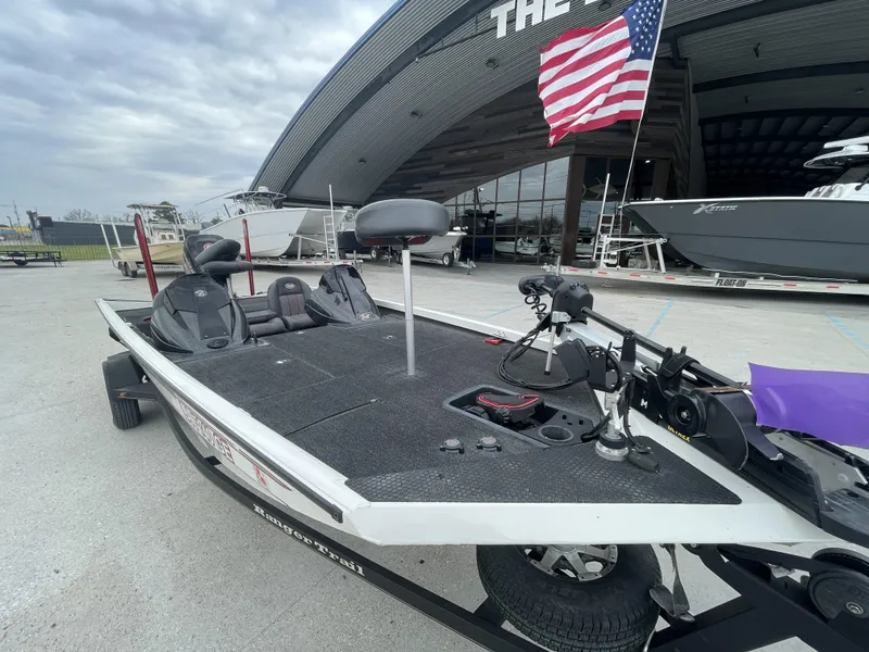 Slide: The Image of 2015 Ranger RT188 boat with American flag, parked near a large building. - 4