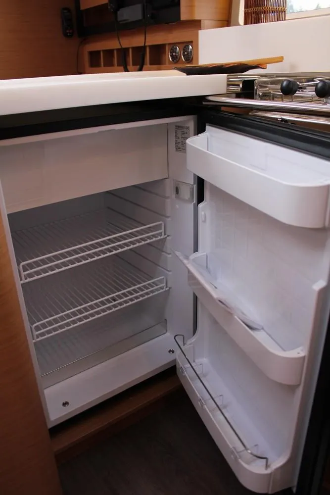 Slide: The Image of 2025 Jeanneau Sun Odyssey 440 yacht interior with open refrigerator showing shelves. - 18