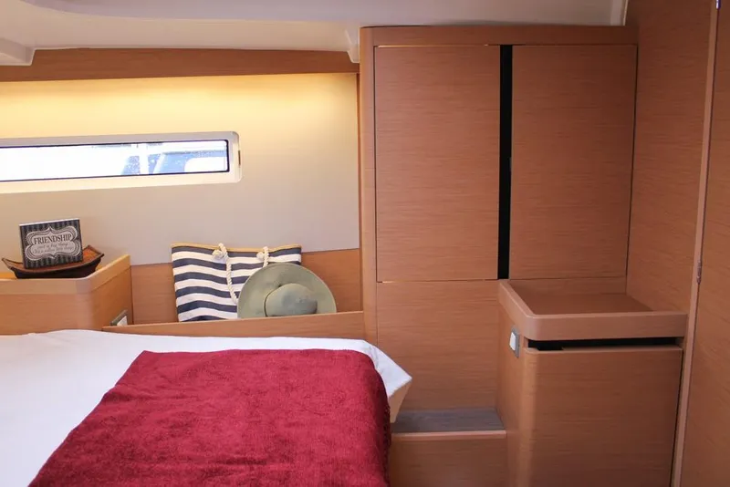Slide: The Image of 2025 Jeanneau Sun Odyssey 440 cabin interior with wooden finish and cozy bedding. - 8