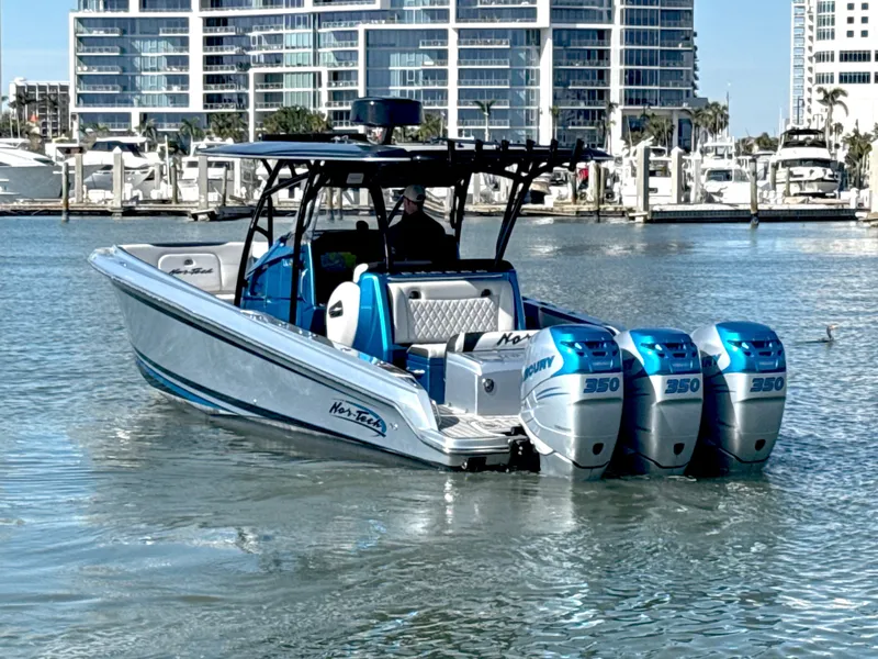 Slide: The Image of 2020 Nor-Tech 340 Sport Open Center Console boat with triple Mercury engines in a marina. - 2