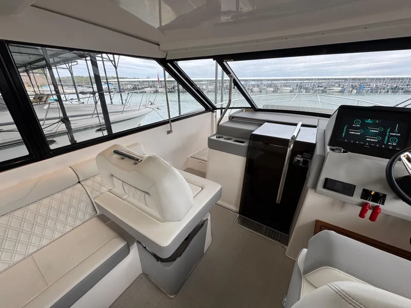 Slide: The Image of 2023 Regal 360 Grande Coupe interior with modern helm and seating, overlooking marina. - 14