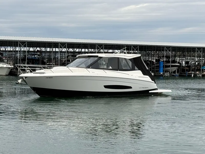 Slide: The Image of 2023 Regal 360 Grande Coupe yacht on calm water near a marina. - 4