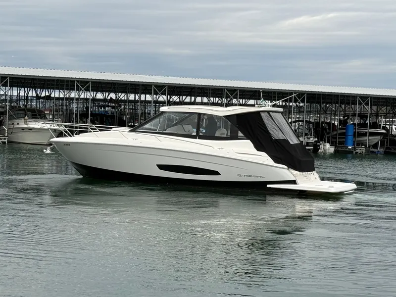 Slide: The Image of 2023 Regal 360 Grande Coupe boat docked in marina, overcast sky. - 5