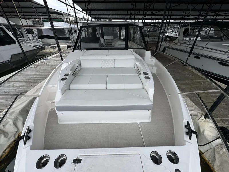 Slide: The Image of 2023 Regal 360 Grande Coupe boat with spacious seating in a marina setting. - 6