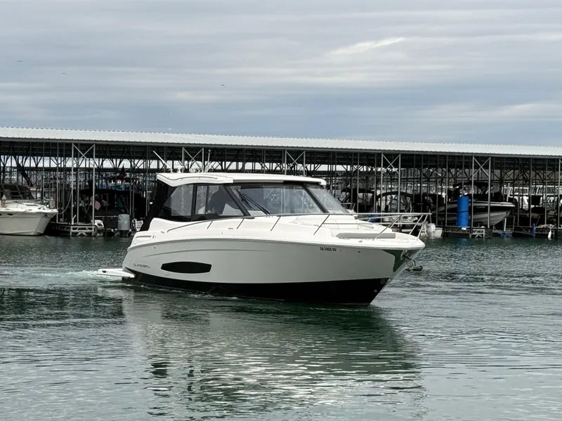 Slide: The Image of 2023 Regal 360 Grande Coupe yacht cruising near marina under cloudy sky. - 9