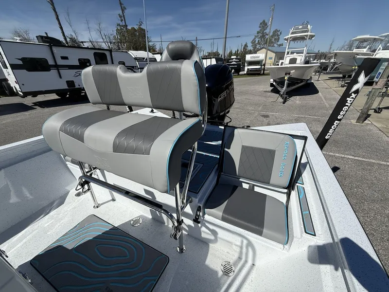 Slide: The Image of 2025 Xpress Hyper-Lift Series H20B boat console with gray seating in a marina setting. - 9