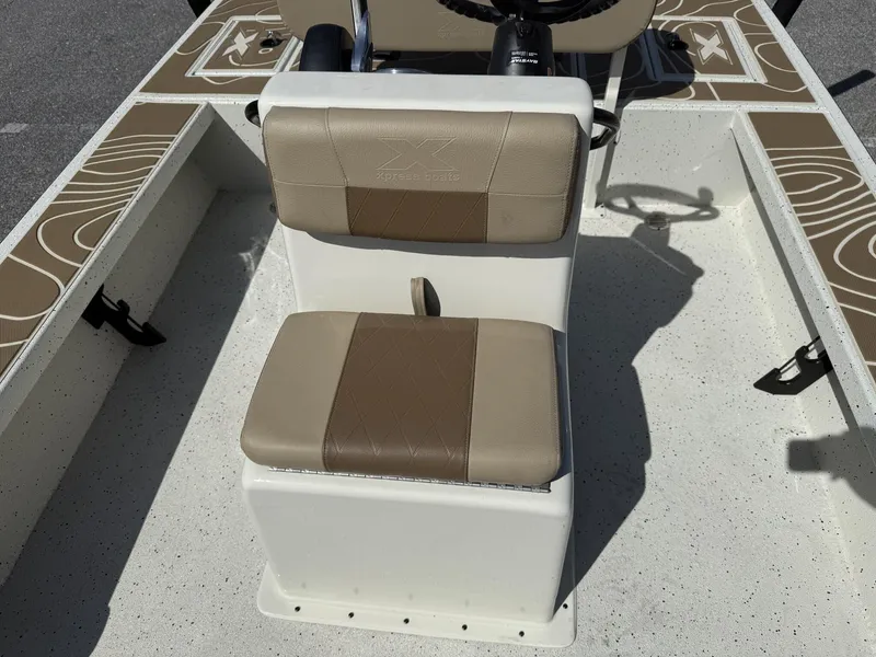 Slide: The Image of 2025 Xpress Skiff 185 boat interior with beige seating and steering console. - 7