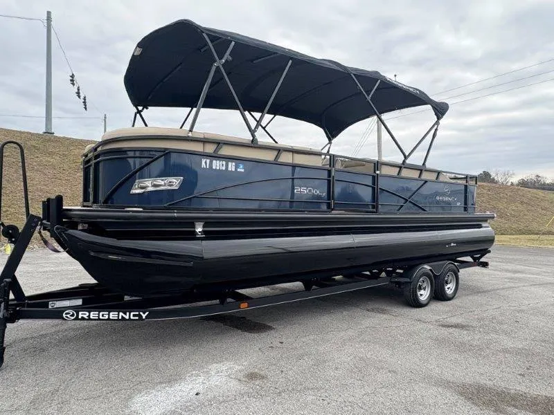 Slide: The Image of 2020 Regency 250 DL3 pontoon boat on trailer, parked outdoors under cloudy sky. - 24