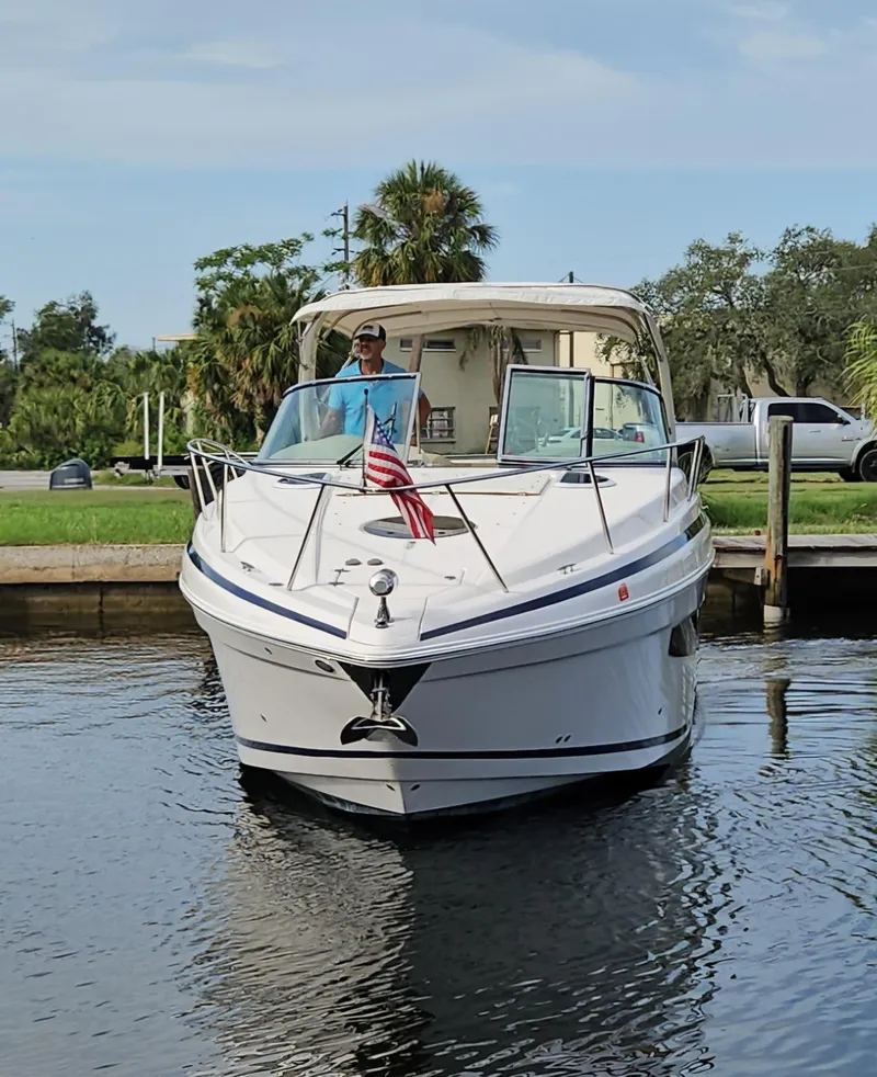 Slide: The Image of 2018 Regal 33 XO boat docked on a calm waterway, featuring sleek design and American flag. - 27