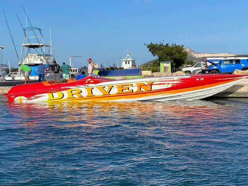 Slide: The Image of 2002 Cigarette ROUGH RIDER speedboat, vibrant "DRIVEN" design, docked at marina. - 5