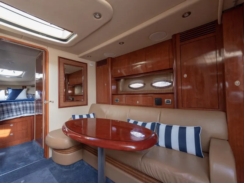 Slide: The Image of 2005 Sea Ray 390 Sundancer interior with wood finish, beige seating, and striped cushions. - 21