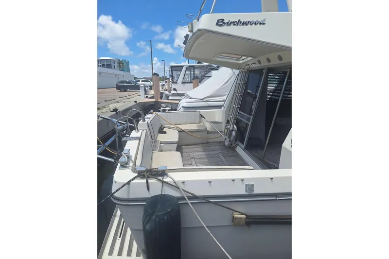 Slide: The Image of 1988 Birchwood 44TS yacht docked at marina, featuring spacious deck and seating area. - 4