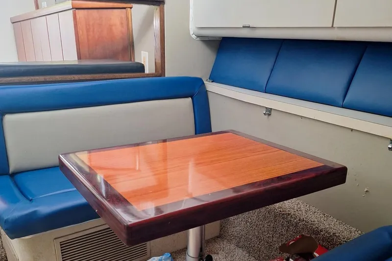 Slide: The Image of Interior of a 1992 Silverton 34 Convertible with blue seating and wooden table. - 10