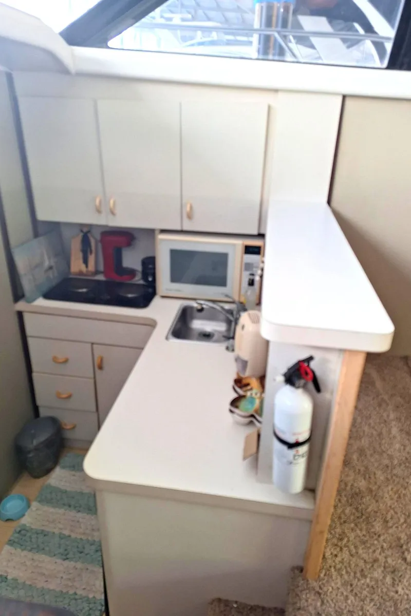 Slide: The Image of 1992 Silverton 34 Convertible yacht kitchen with cabinets, sink, microwave, and fire extinguisher. - 12