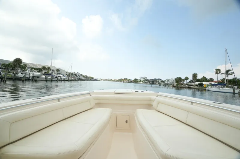 Slide: The Image of 2019 Grady-White Canyon 336 boat on calm water, showcasing spacious seating and scenic marina view. - 12