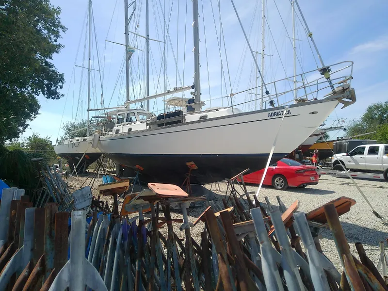 Slide: The Image of 1971 Morgan 40 Cruising Ketch sailboat on land, surrounded by anchors and vehicles. - 2