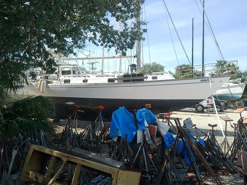 Slide: The Image of 1971 Morgan 40 Cruising Ketch sailboat on land, surrounded by trees and equipment. - 3