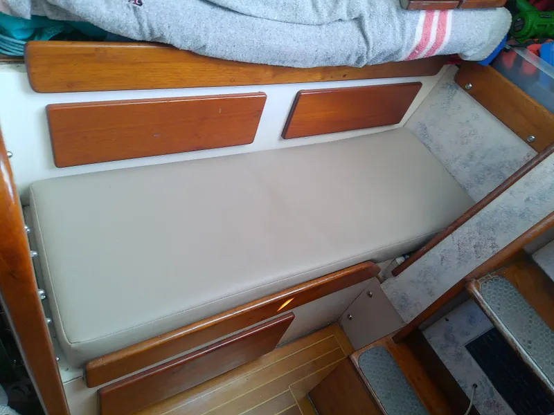 Slide: The Image of Interior view of a 1971 Morgan 40 Cruising Ketch with a cushioned bench and wooden accents. - 49