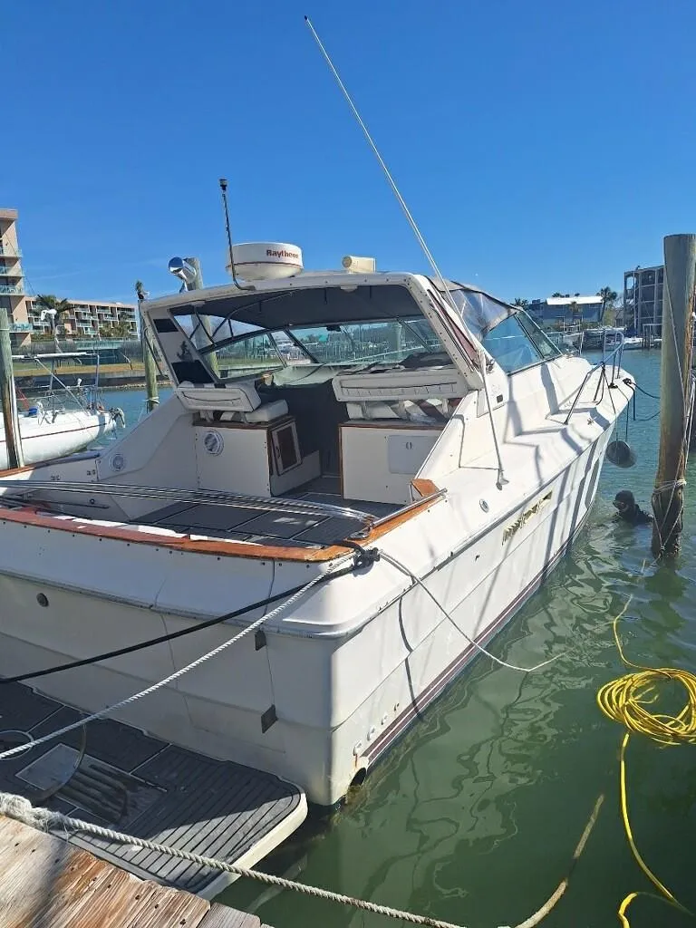 Slide: The Image of 1985 Sea Ray 390 Express Cruiser docked in a marina under clear blue skies. - 0