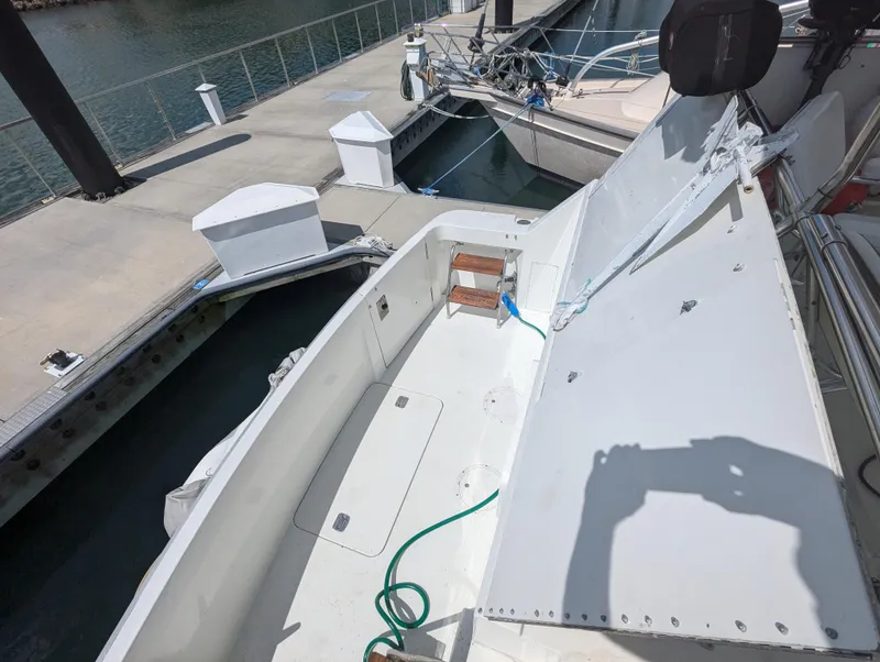 Slide: The Image of 1996 Hatteras 42 Cockpit MY at dock, open hatch, hose visible. - 32