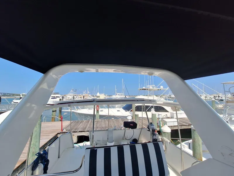 Slide: The Image of 1996 Hatteras 42 Cockpit MY at marina, featuring striped seating and covered deck. - 34