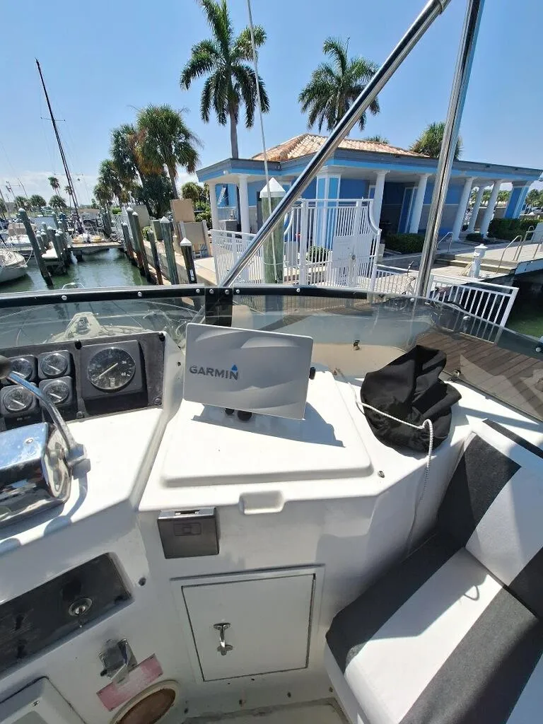 Slide: The Image of 1996 Hatteras 42 Cockpit MY boat interior with Garmin navigation, docked near palm trees and blue building. - 39
