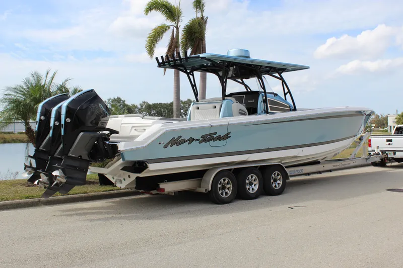 Slide: The Image of 2021 Nor-Tech 390 Sport Center Console boat on trailer, parked near palm trees. - 16