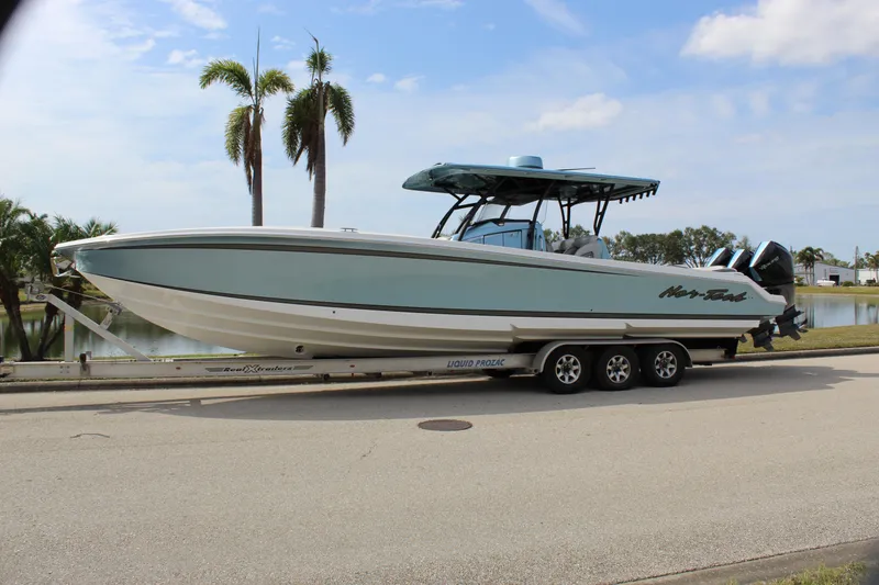Slide: The Image of 2021 Nor-Tech 390 Sport Center Console boat on trailer, parked near palm trees. - 2