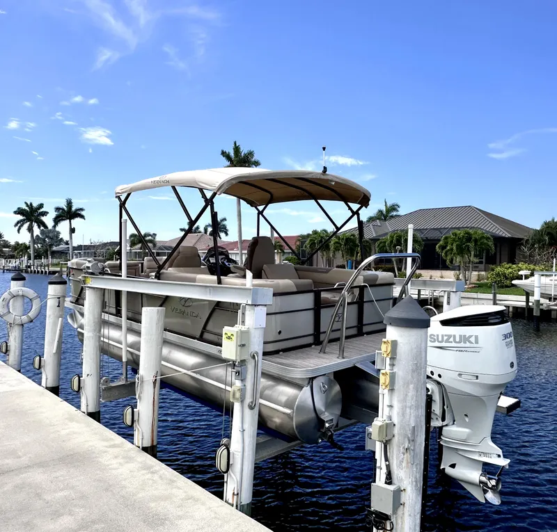 Slide: The Image of 2022 Veranda Relax VR22RC pontoon boat docked with Suzuki outboard motor. - 0