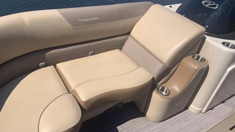 Slide: The Image of 2022 Veranda Relax VR22RC boat seating with cup holders, beige upholstery, and water backdrop. - 12