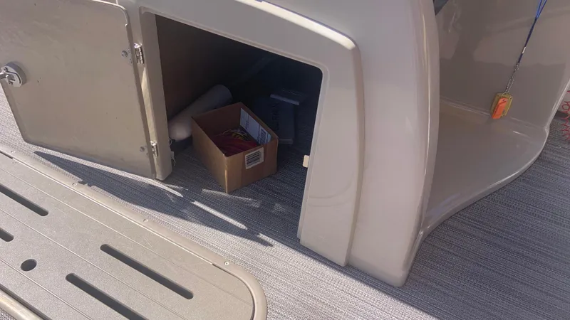 Slide: The Image of Open storage compartment on 2022 Veranda Relax VR22RC boat with items inside. - 17