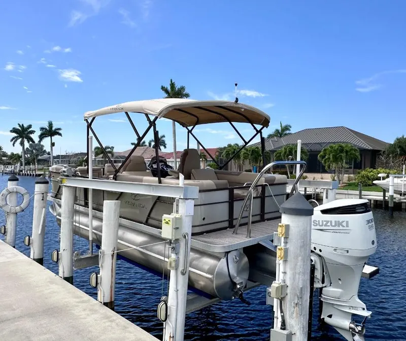 Slide: The Image of 2022 Veranda Relax VR22RC pontoon boat docked with Suzuki outboard motor. - 2