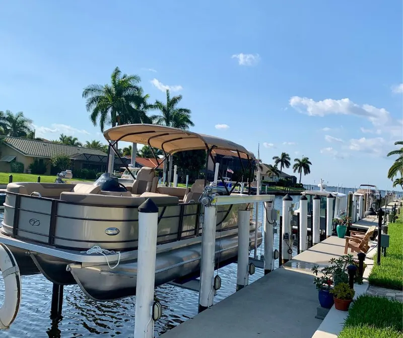 Slide: The Image of 2022 Veranda Relax VR22RC pontoon boat docked by a sunny waterfront with palm trees. - 3