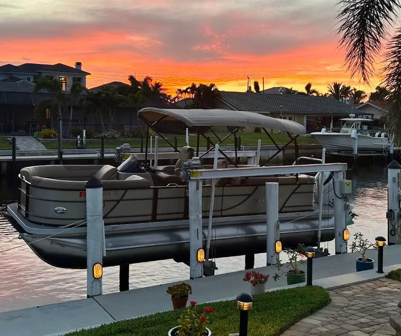 Slide: The Image of 2022 Veranda Relax VR22RC pontoon boat docked at sunset, with vibrant sky and waterfront view. - 4