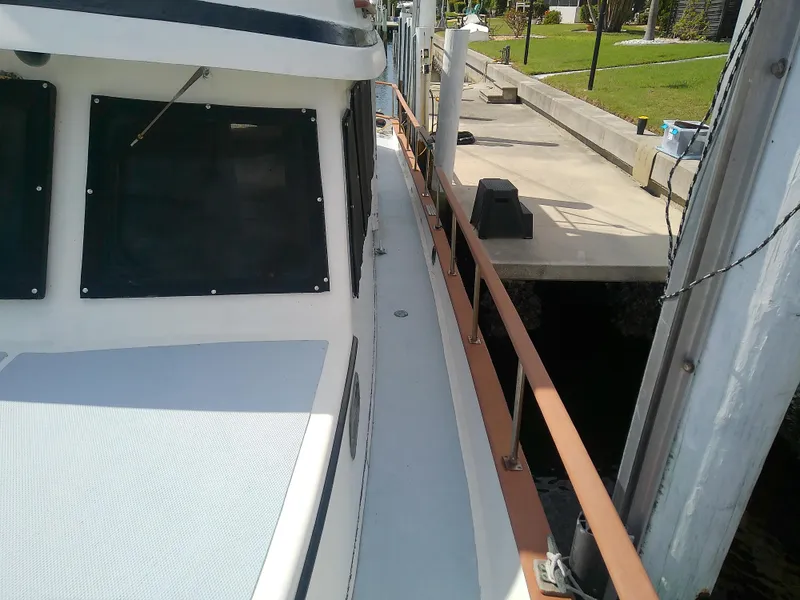 Slide: The Image of 1987 Albin 40 boat docked, showing side deck and windows. - 16